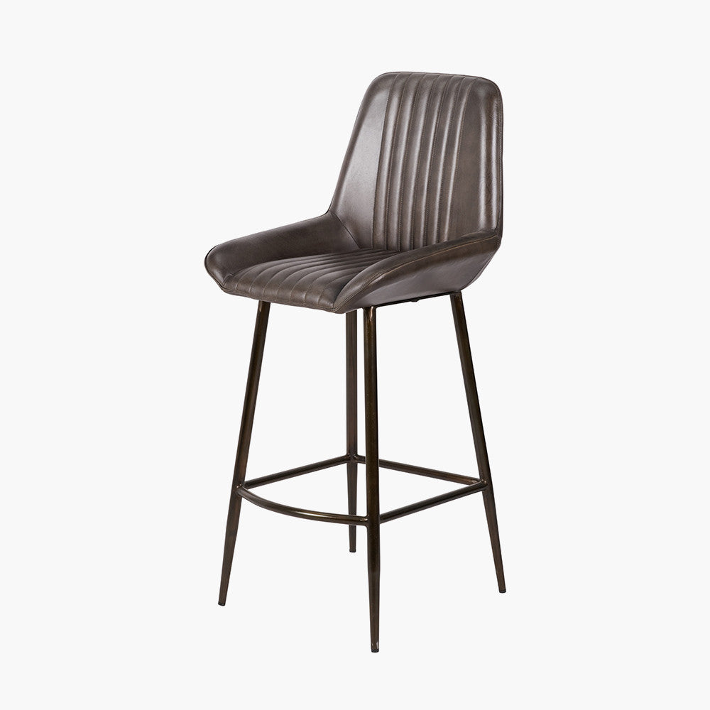 Upholstered in deep peppercorn-toned leather with ribbed cushioning and bronze metal frame, this handcrafted bar stool offers both comfort and visual impact. Shop online today at www.nobleandnook.co.uk