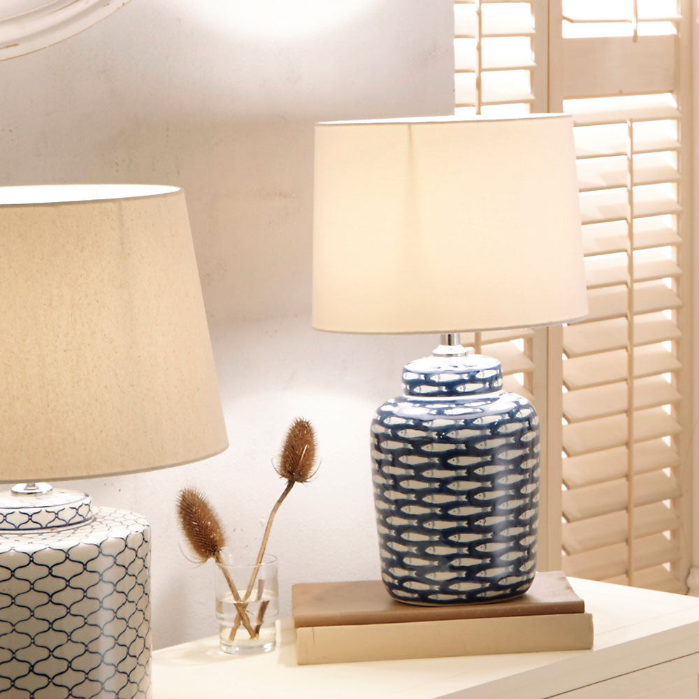 Shop Ceramic Base with repeated fish motif with soft yet striking presence tapered cream cotton shade. Perfect for coastal or nautical interiors. Shop online today at www.nobleandnook.co.uk