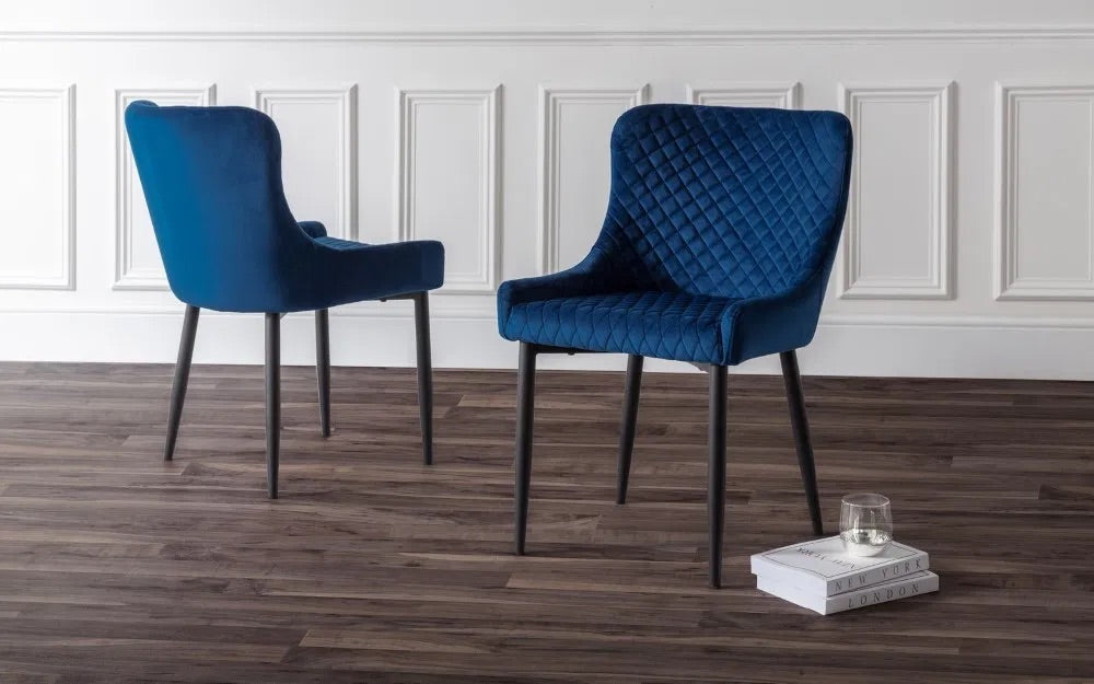 Add a sophisticated touch with the Luxe Blue Velvet Dining Chairs. Upholstered in rich blue velvet with intricate quilted detailing and black-painted legs. Shop online today at www.nobleandnook.co.uk
