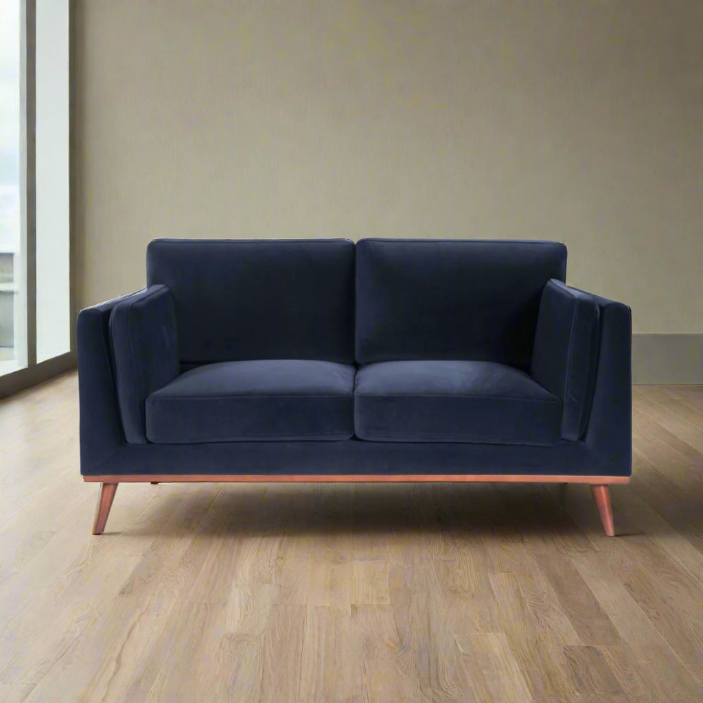 Shop the Mickey 2 seater sofa in Midnight Blue velvet with a walnut frame and tapered walnut legs, its a contemporary masterpiece. Shop online today at www.nobleandnook.co.uk