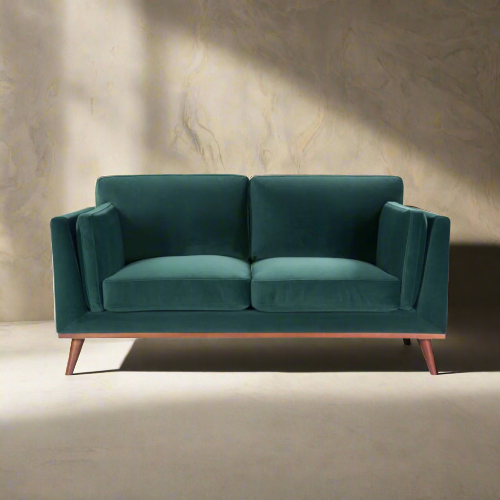 Shop the Mickey 2 seater sofa in on trend Emerald Green velvet with a walnut frame and tapered walnut legs, a contemporary masterpiece. Shop online today at www.nobleandnook.co.uk