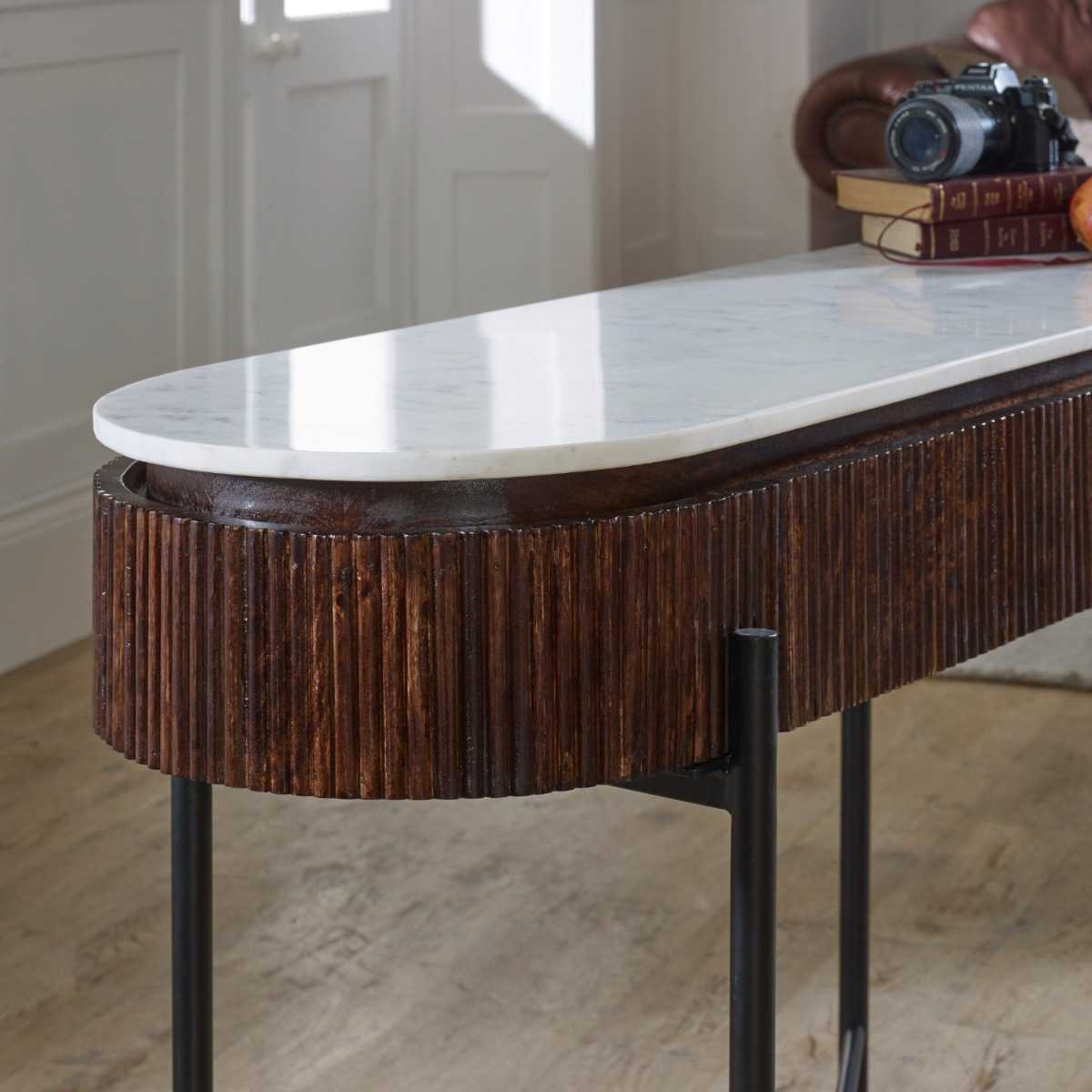 The handmade Opal Console Table with smooth marble top nests within a beautifully fluted mango wood frame, all supported by refined metal legs. H77×W120×D40 cm. Shop online today at www.nobleandnook.co.uk