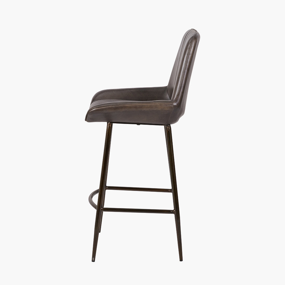 Upholstered in deep peppercorn-toned leather with ribbed cushioning and bronze metal frame, this handcrafted bar stool offers both comfort and visual impact. Shop online today at www.nobleandnook.co.uk
