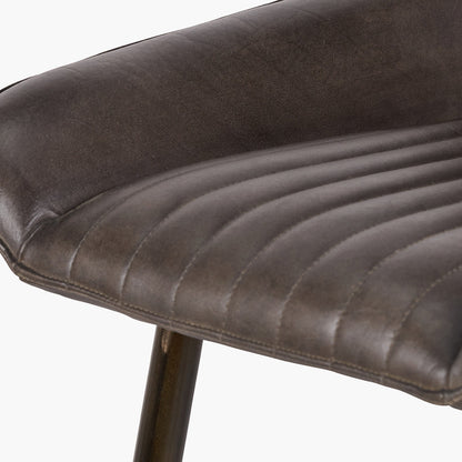 Upholstered in deep peppercorn-toned leather with ribbed cushioning and bronze metal frame, this handcrafted bar stool offers both comfort and visual impact. Shop online today at www.nobleandnook.co.uk