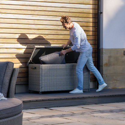 Man organizing outdoor cushions in a storage box on a patio
