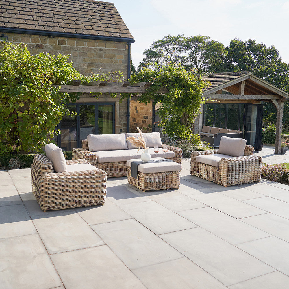 Outdoor patio with wicker furniture and stone building in the background