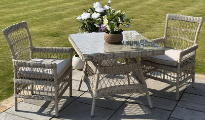 Outdoor patio set with wicker table and chairs on a patio with grass background