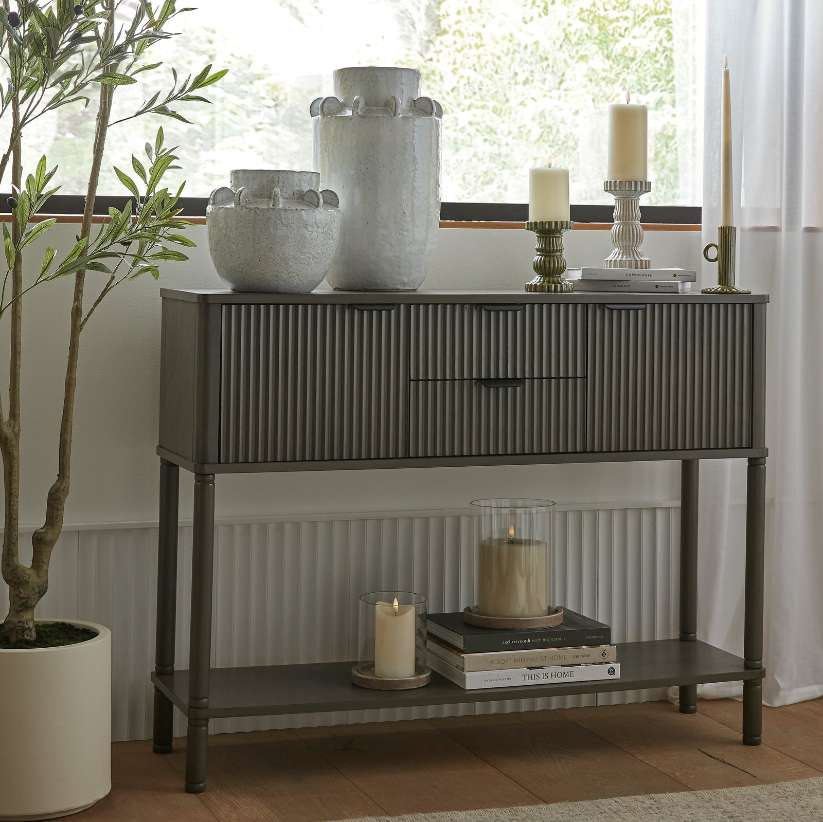 Console table with decorative items including vases and candles in a room setting.