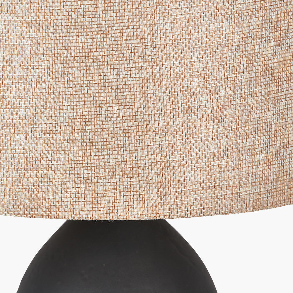 Textured beige lampshade on a black base against a white background