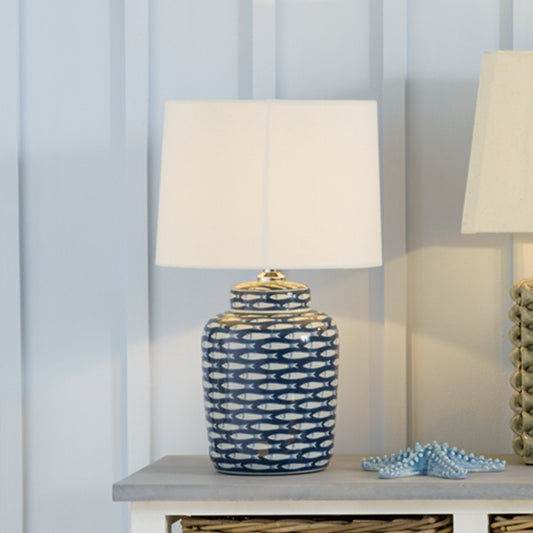 Shop Ceramic Base with repeated fish motif with soft yet striking presence tapered cream cotton shade. Perfect for coastal or nautical interiors. Shop online today at www.nobleandnook.co.uk
