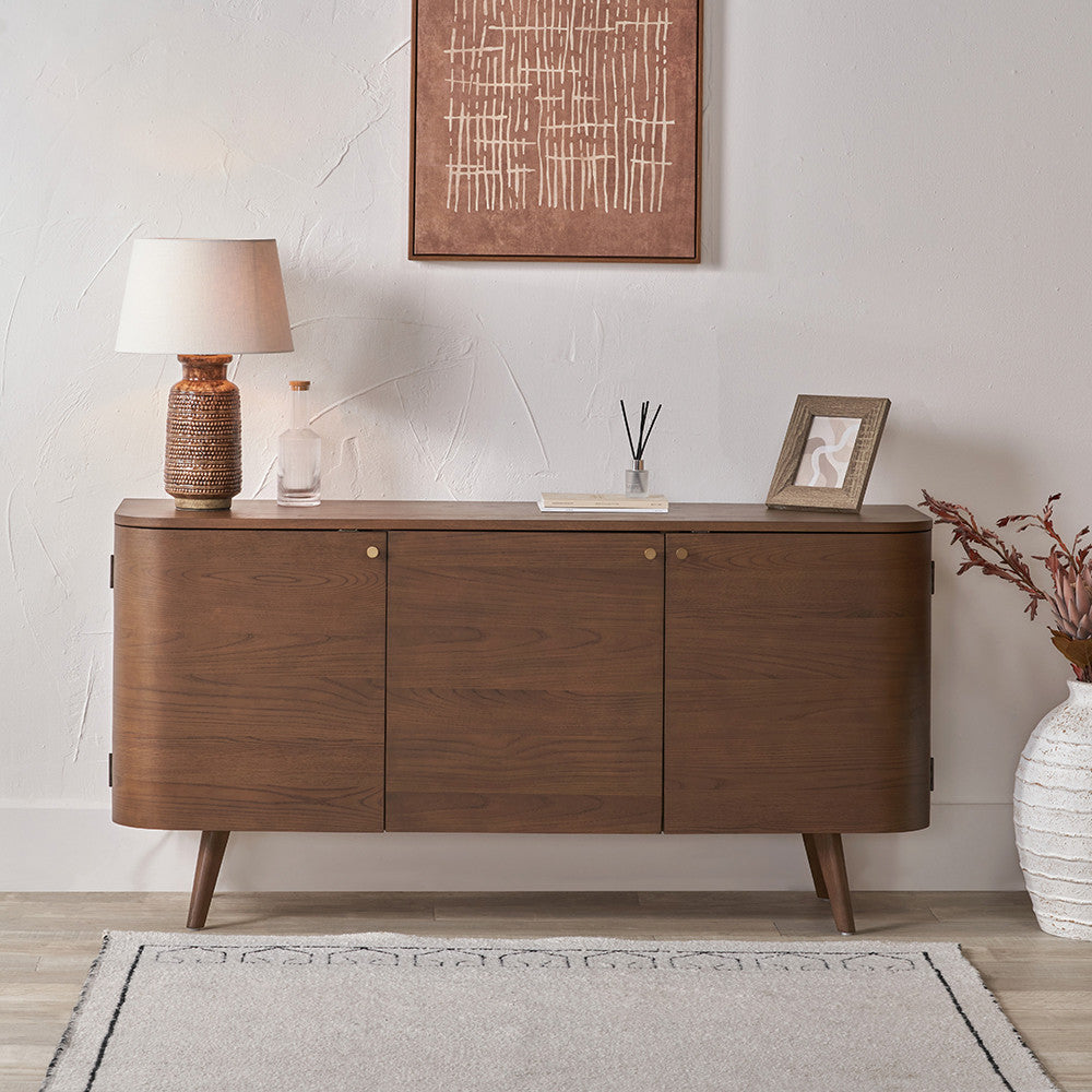 Wooden sideboard in a room with decor elements like a lamp, vase, and abstract painting.