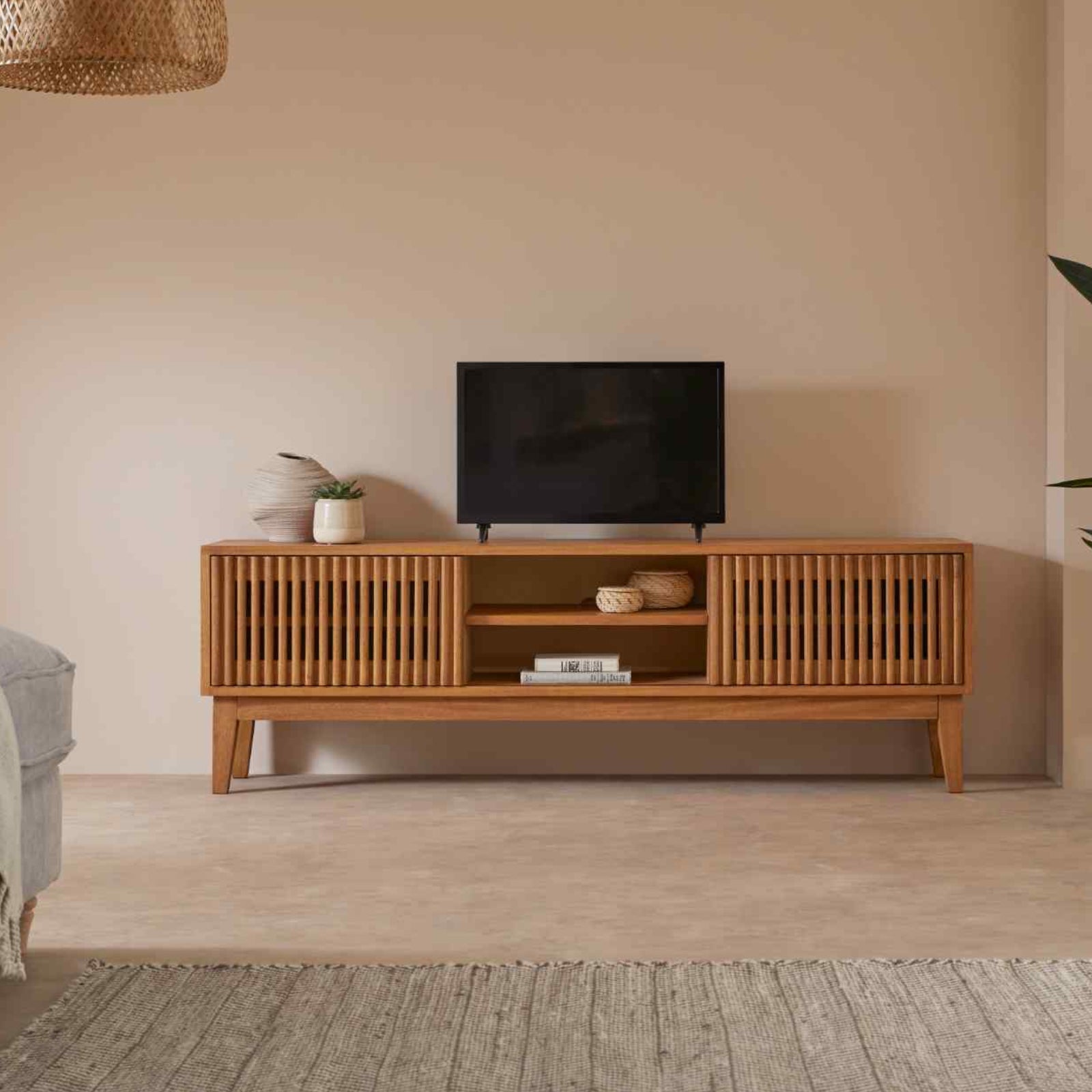 Wooden TV stand with a television in a living room setting.
