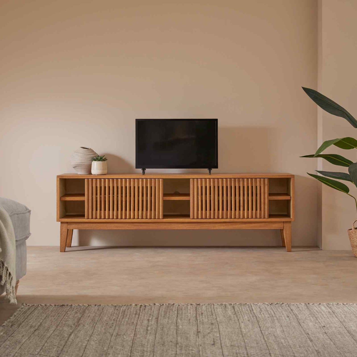 Wooden TV stand with a television in a minimalistic living room.