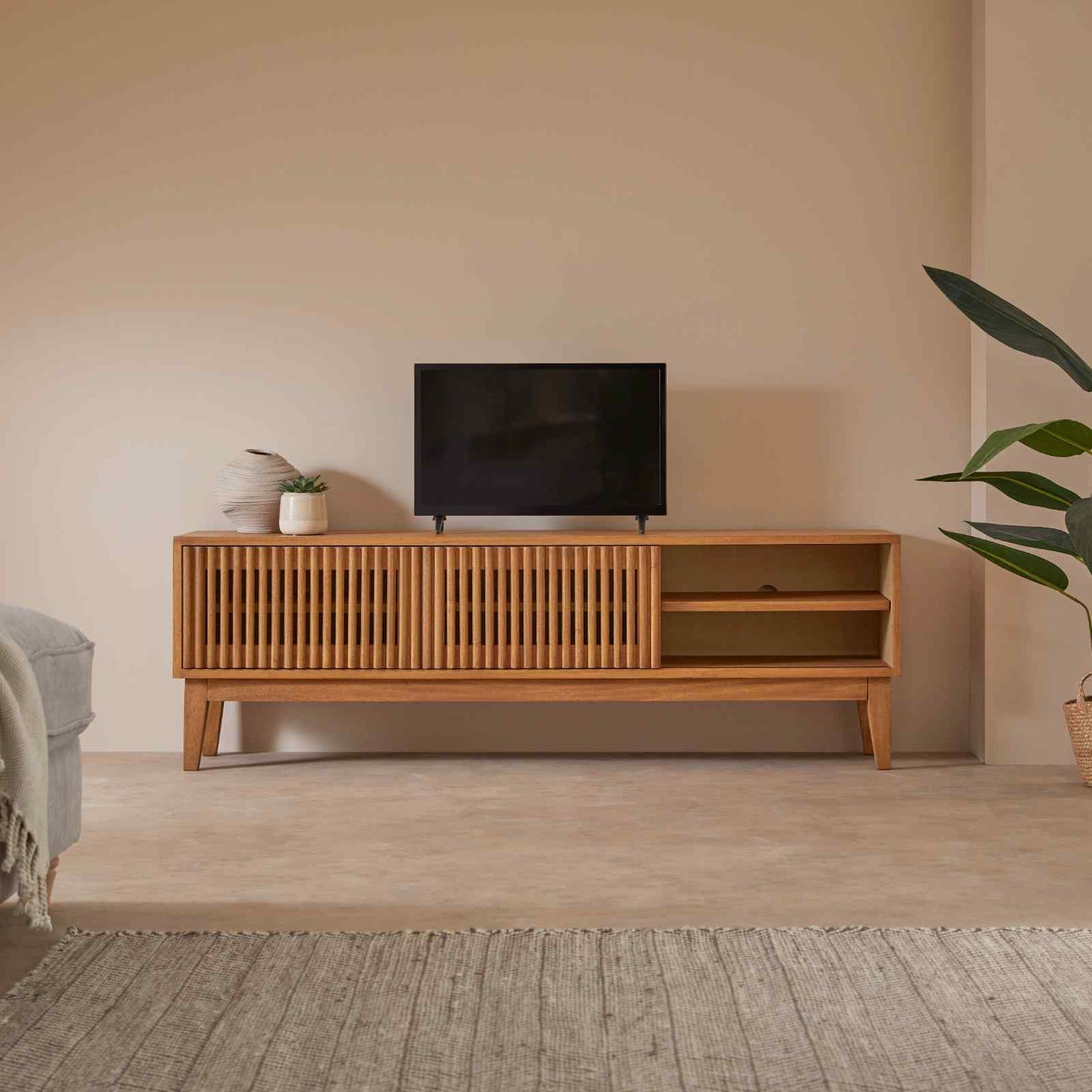 Wooden TV stand with a television in a minimalistic living room.