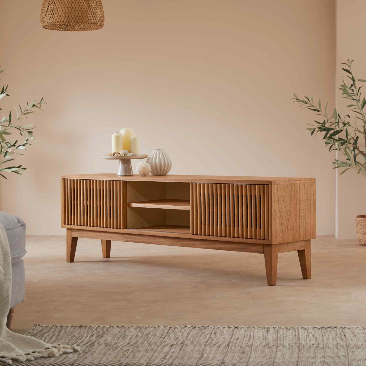 Wooden TV stand in a living room with decorative items and plants.
