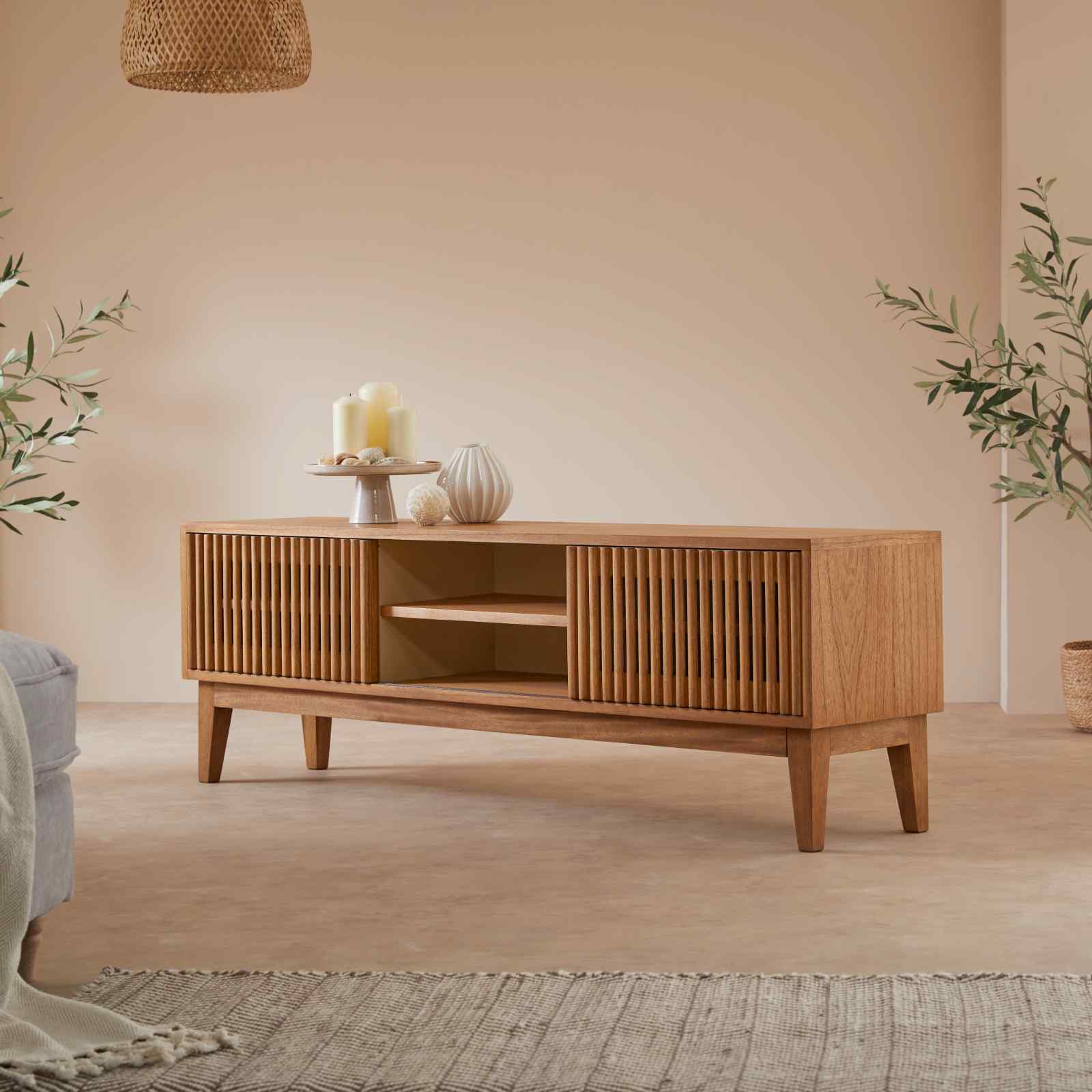 Wooden TV stand in a living room with decorative items and plants.