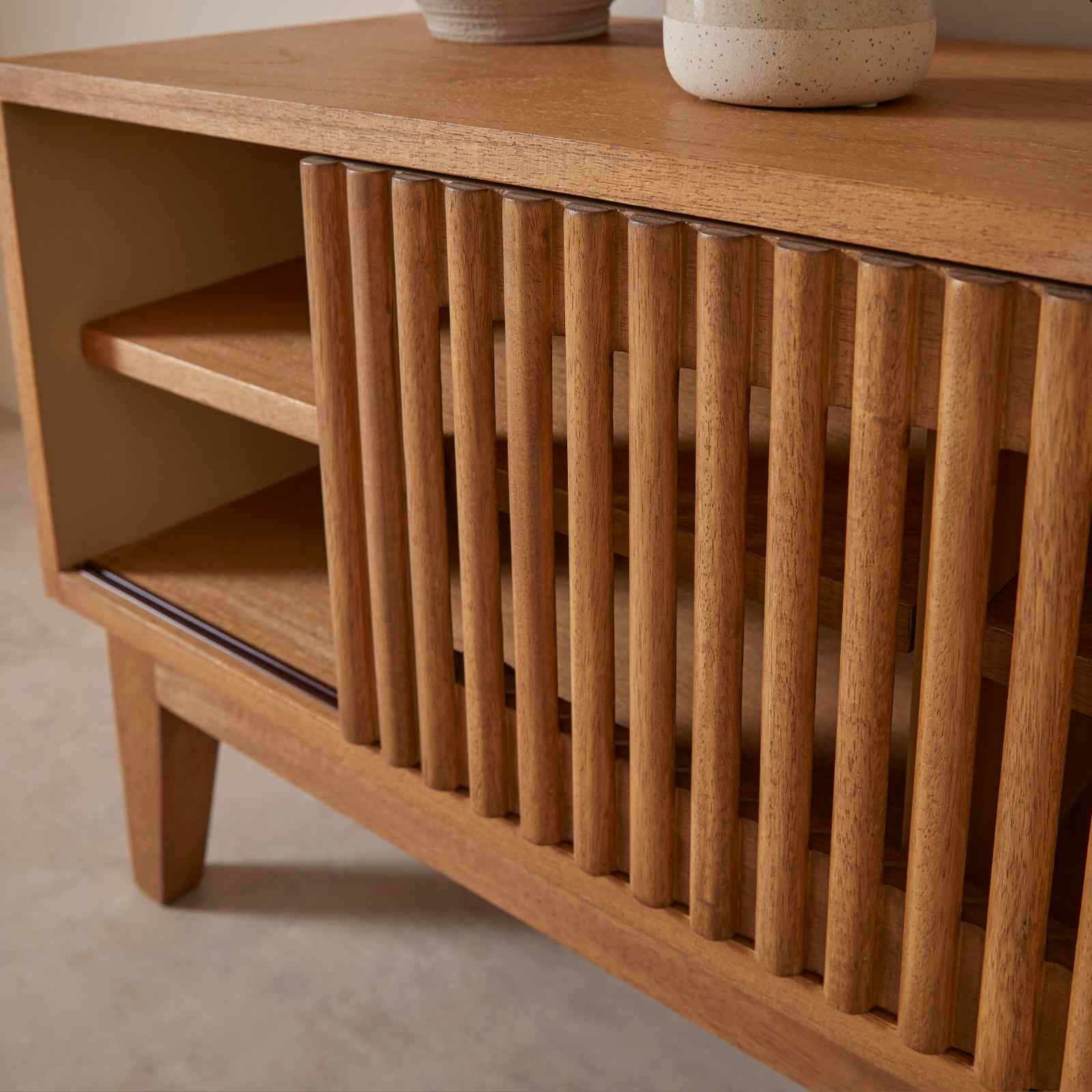 Wooden cabinet with slatted design and two ceramic pots on top