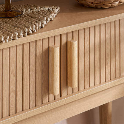 Elevate your interior with the Axel Console Table in an Oak Finish. This stylish table features exquisite fluted detailing, adds depth and sophistication to any living space. Shop online today at www.nobleandnook.co.uk