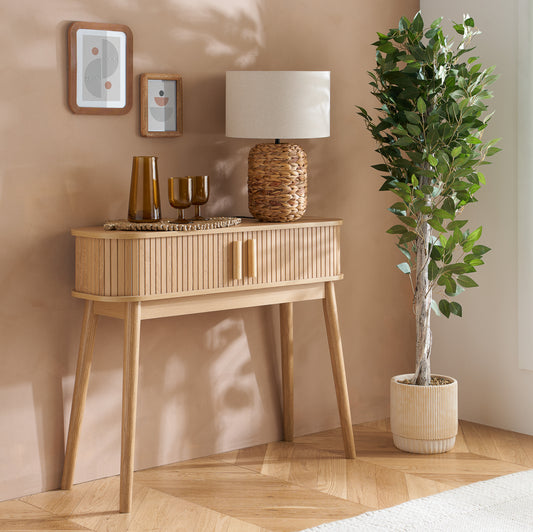 Elevate your interior with the Axel Console Table in an Oak Finish. This stylish table features exquisite fluted detailing, adds depth and sophistication to any living space. Shop online today at www.nobleandnook.co.uk