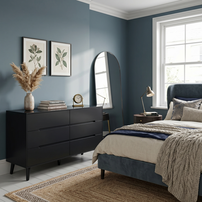 Modern bedroom with dark dresser, bed, and decorative elements.