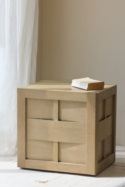 Wooden side table with a book on top against a neutral wall