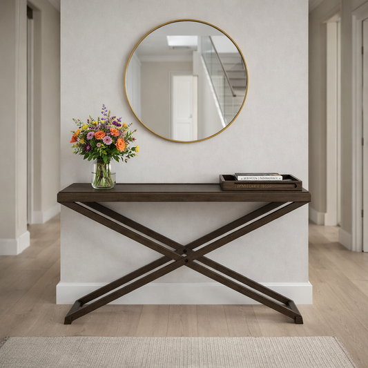 Wooden console table with a round mirror above it in a hallway.