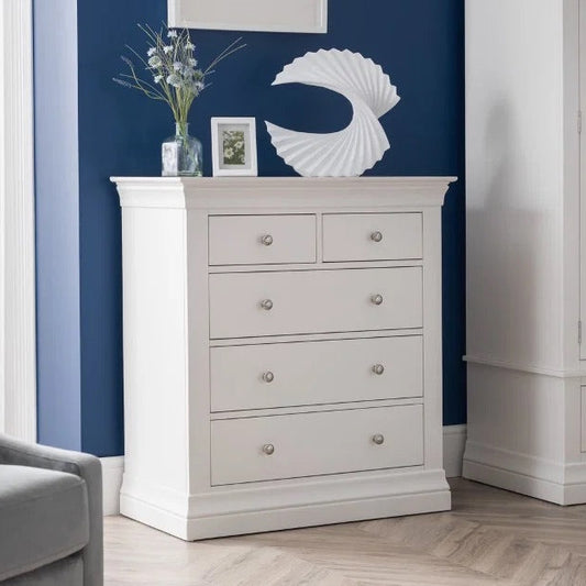 White dresser with decorative items in a room with a blue wall and gray furniture.