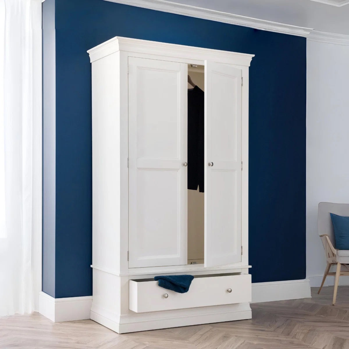 White wardrobe with a mirror against a blue wall in a room.