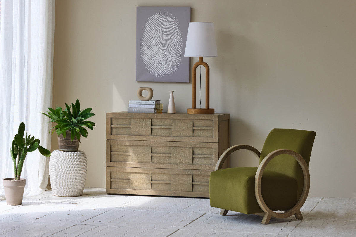 Modern living room with wooden dresser, green armchair, and decorative items.