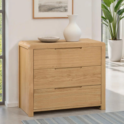 Wooden dresser with two drawers in a room with a plant and framed picture.