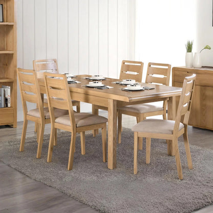 Wooden dining table set with chairs in a room with a bookshelf and decorative items.