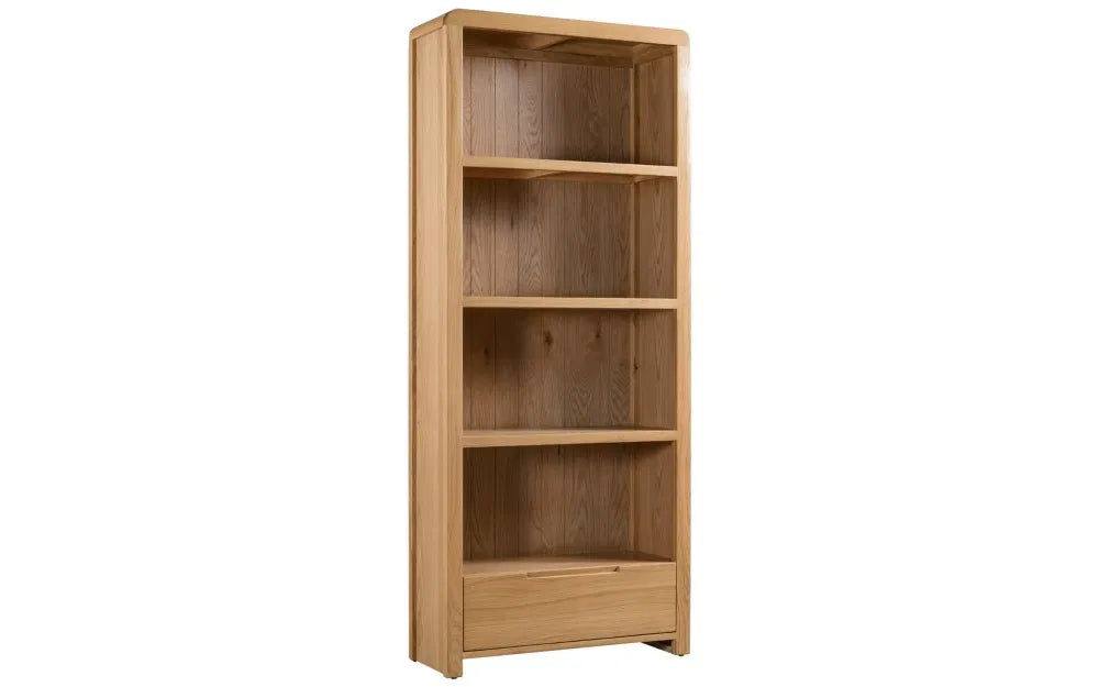 The Curve Tall Solid Oak Bookcase, a stylish and practical addition to any modern home. Its clean lines and gently curved edging bring a touch of retro charm to your living or dining space. Shop online at www.nobleandnook.co.uk