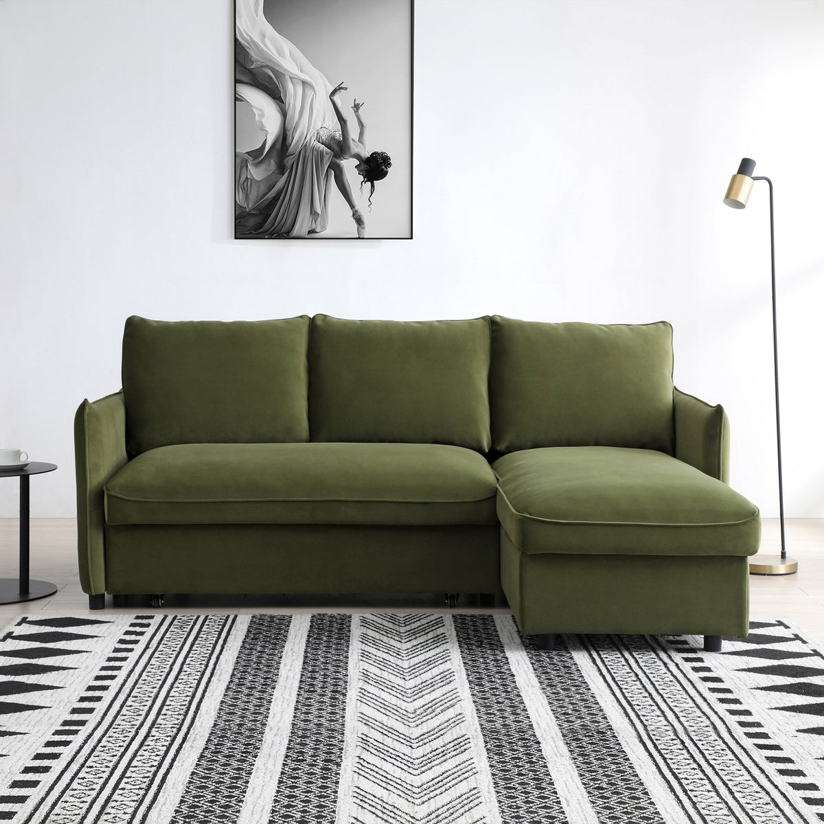 Green sectional sofa in a room with a patterned rug and artwork on the wall.