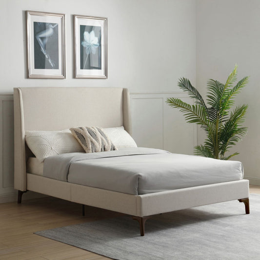 A modern upholstered bed frame in a bright, minimalist bedroom. The bed features a tall, wingback-style headboard and matching low-profile footboard in a light beige fabric, supported by dark wood legs.