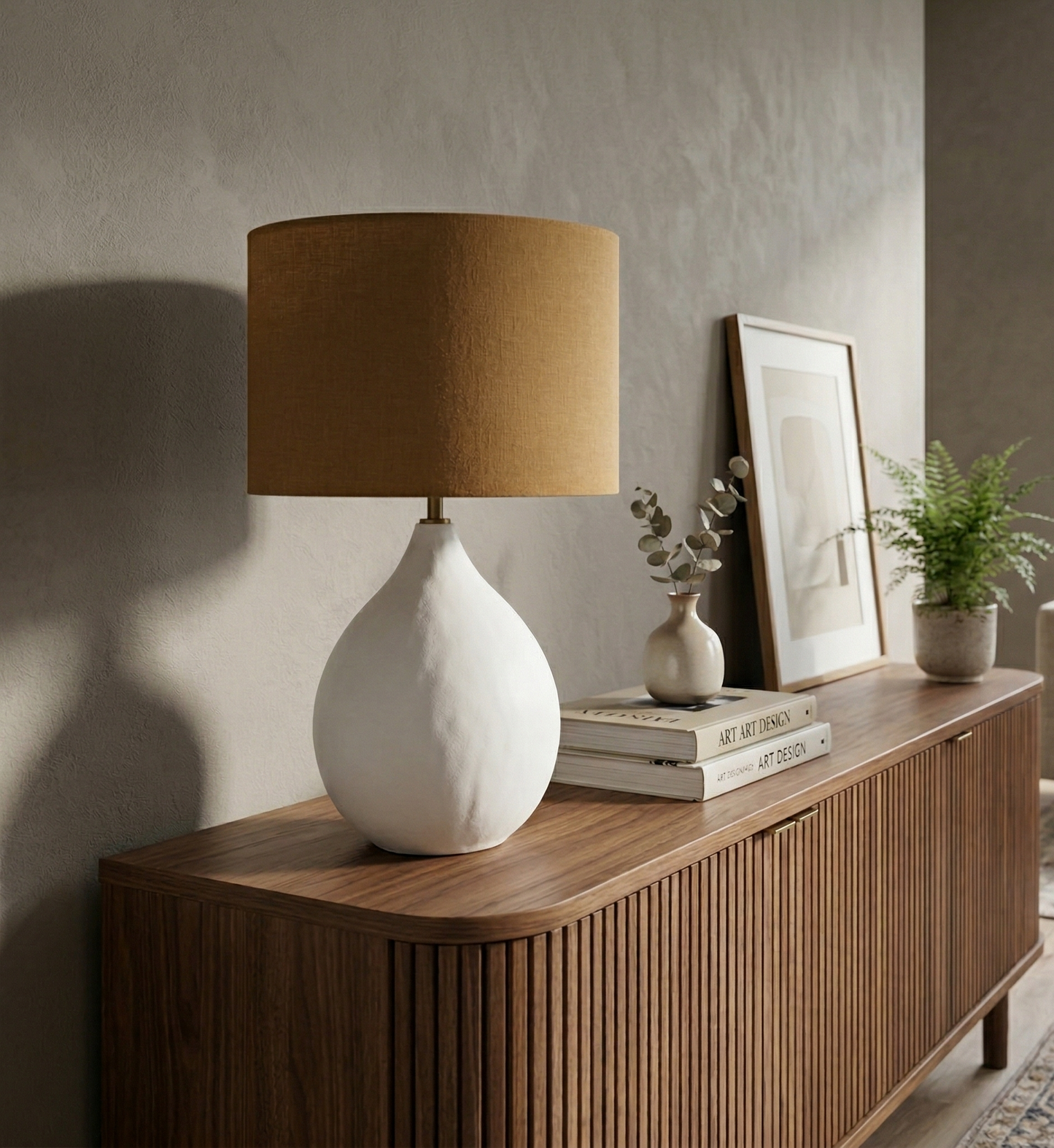 White ceramic lamp with a brown lampshade on a wooden sideboard in a living room.