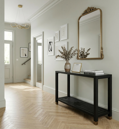 Modern interior with a black console table, gold-framed mirror, and decorative items.