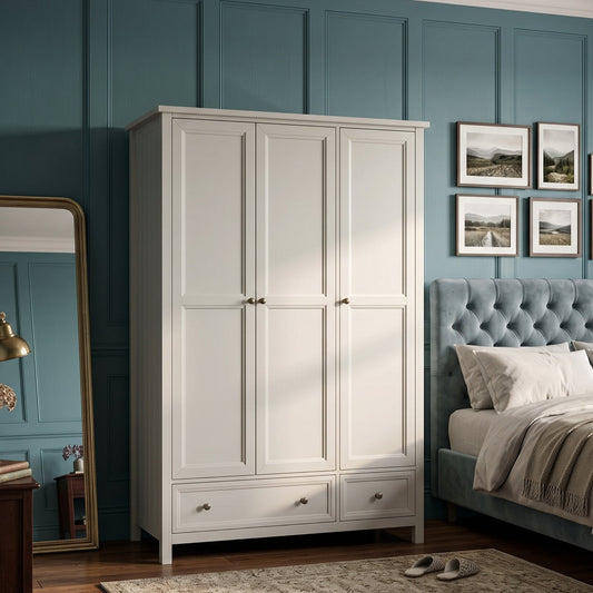 A tall white 3-door wardrobe with two lower drawers, styled in a bedroom next to a blue tufted bed, a wooden side table with a mirror, and teal paneled walls.