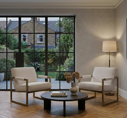 Modern living room with two beige armchairs and a round dark coffee table.