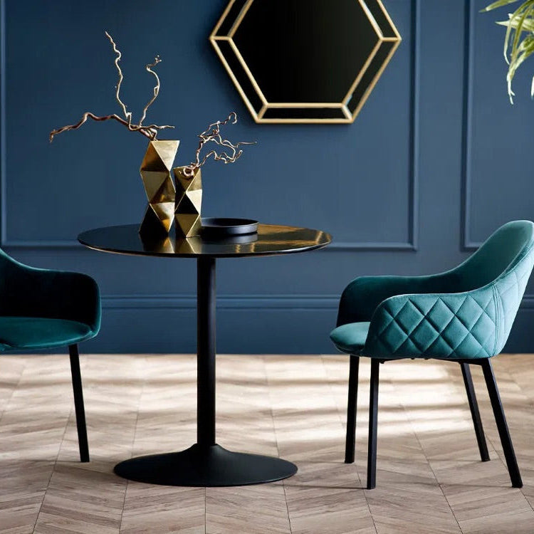 Two teal chairs around a black table in a room with blue walls and decorative elements.