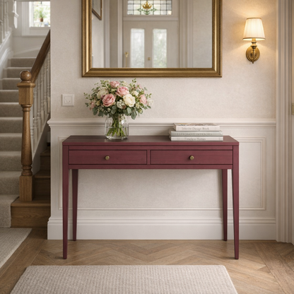 Maroon console table with a vase of flowers and books in a home setting.