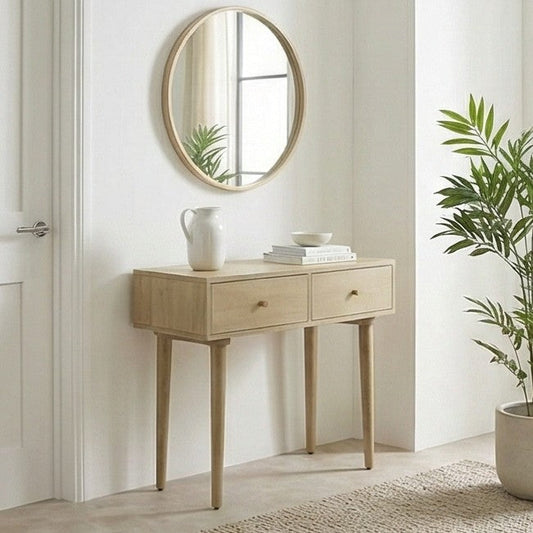Wooden console table with round mirror and decor items in a room with a plant.