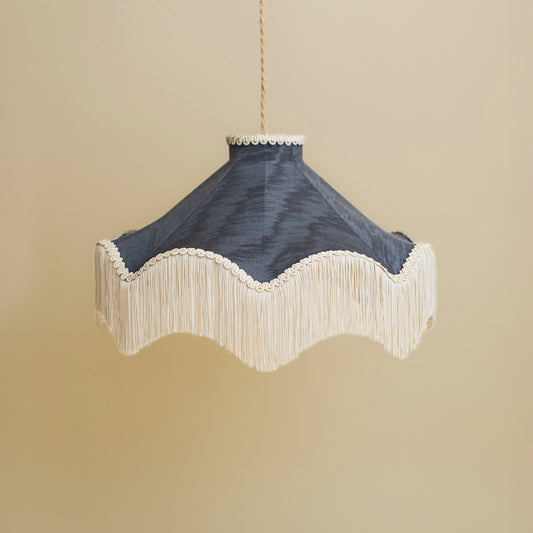 Decorative lamp with blue shade and beige fringe on a beige background