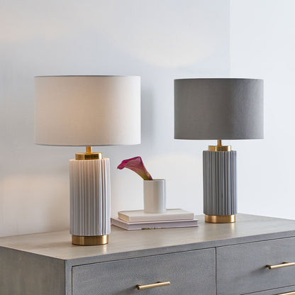 Two table lamps with ribbed design and gold bases on a dresser.