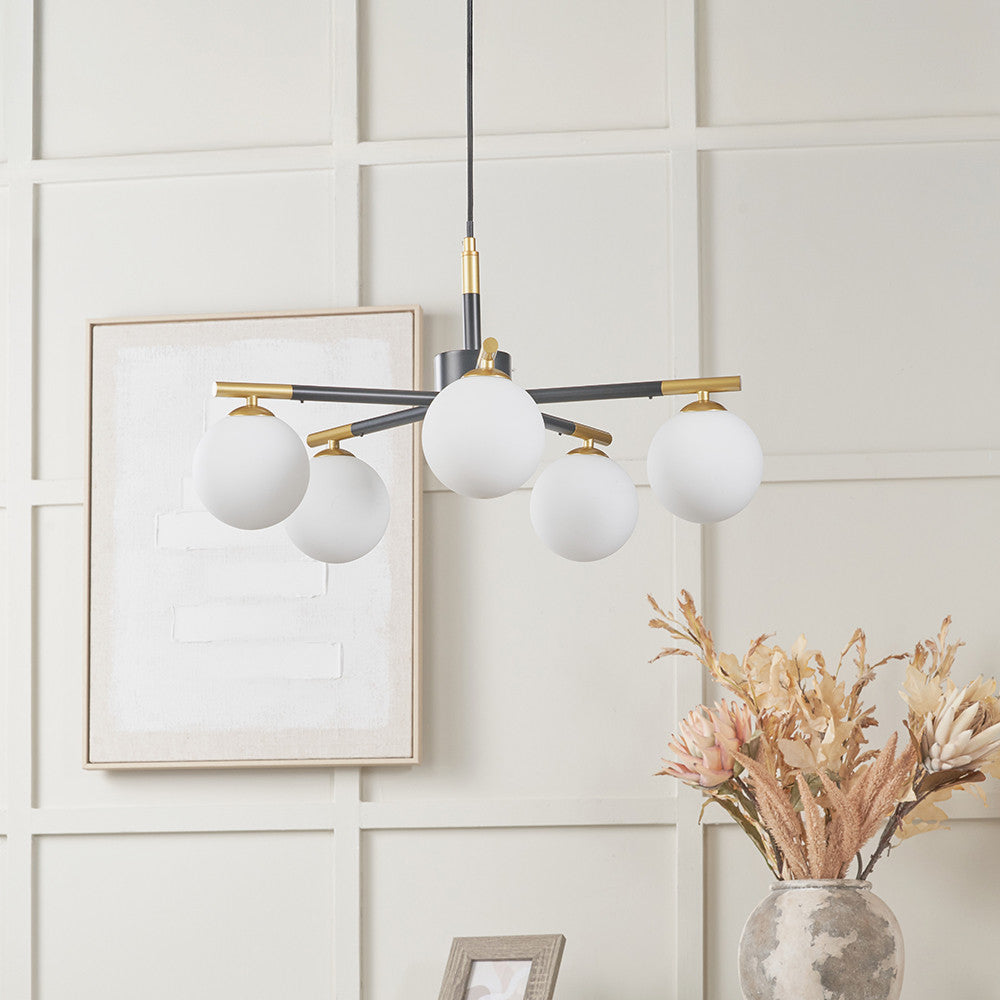 Modern chandelier with white spherical lights on a neutral wall with decorative elements.