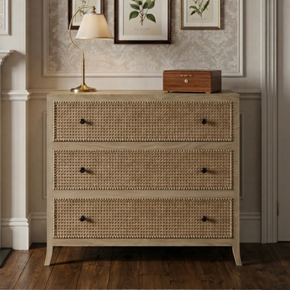 A bedroom with a rattan dresser, framed botanical art, and decorative elements.