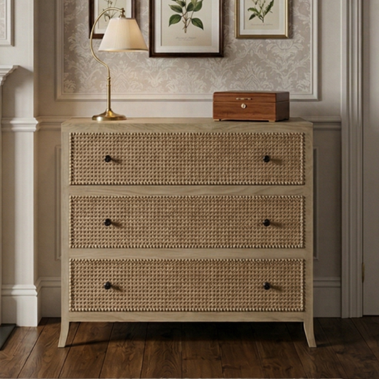 A bedroom with a rattan dresser, framed botanical art, and decorative elements.