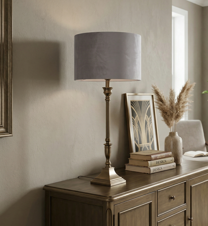 Decorative setting with a lamp, books, and a plant on a wooden sideboard in a room.
