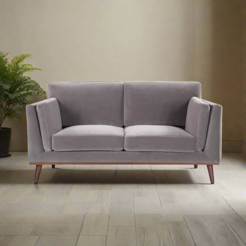 Shop the Mickey 2 seater sofa in Stone Grey velvet with a walnut frame and tapered walnut legs, a contemporary masterpiece. Shop online today at www.nobleandnook.co.uk
