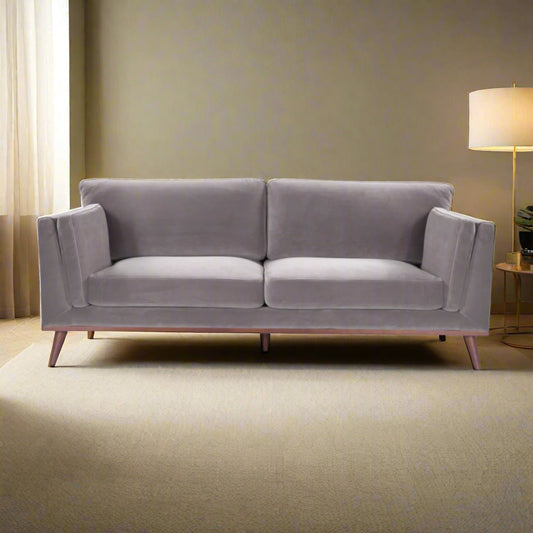 Shop the Mickey 3 Seat Sofa in a fashionable grey velvet hue with tapered walnut legs. This is a contemporary masterpiece. Shop online today at www.nobleandnook.co.uk